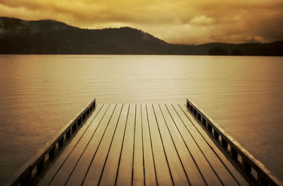 Pier over lake against sky during sunset