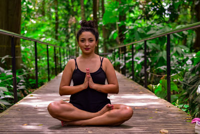 Portrait of woman practicing yoga on footbridge