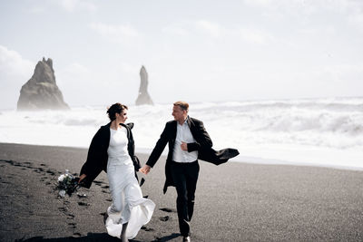 Full length of couple walking on beach against sea