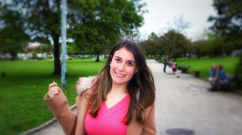 Portrait of a smiling young woman against trees