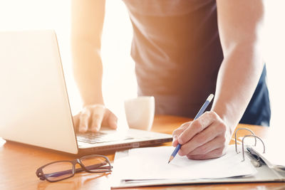Midsection of man using laptop on table