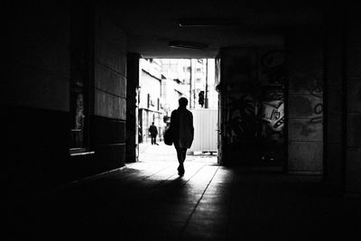 Rear view of silhouette man walking towards entrance