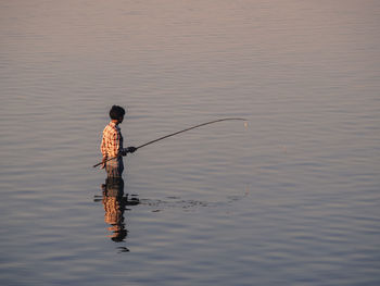 Rear view of man fishing in lake