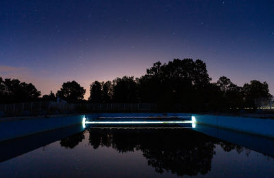 Reflection of trees in swimming pool at night