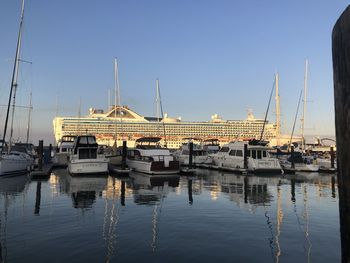 Boats moored at harbor against clear sky