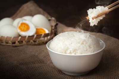 Eating rice by using chopsticks on wooden background