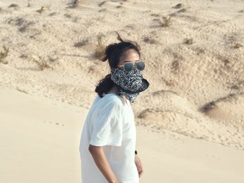 Woman with mouth covered standing in desert