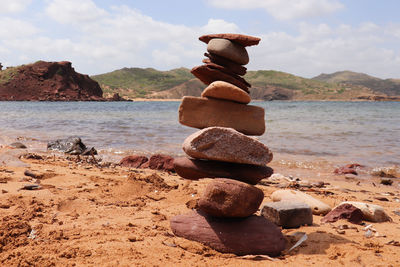 Stack of pebbles on beach against sky