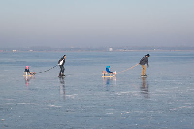 People enjoying on beach against sky