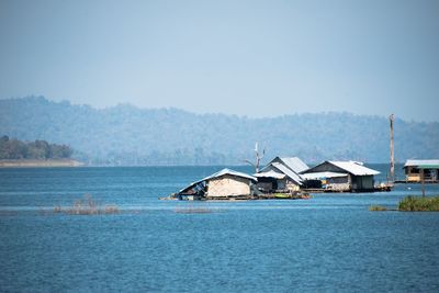 Houses by sea against clear sky