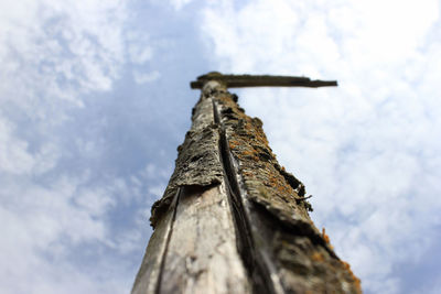 Low angle view of wooden pole against cloudy sky