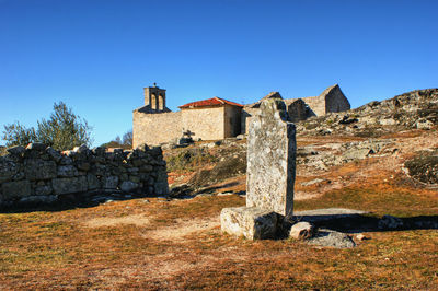 Old house on field against clear blue sky