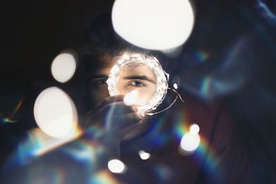 Portrait of man holding illuminated string lights