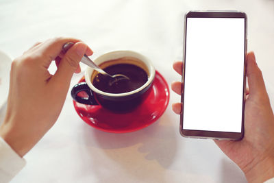 Midsection of man holding coffee cup and smart phone