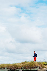 Man walking on grass against sky