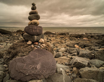 Rocks on beach against cloudy sky