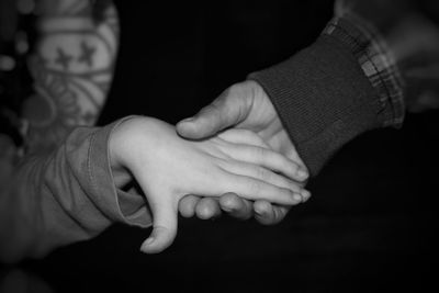 Close-up of cropped couple holding hands at night