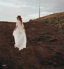 Midsection of woman standing on field against sky