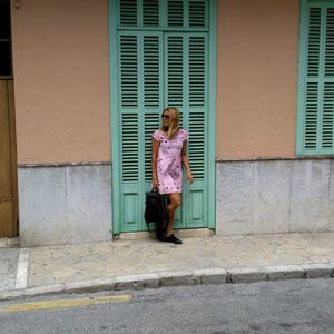 Young woman standing against closed door of building