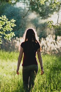 Woman standing on grass against trees