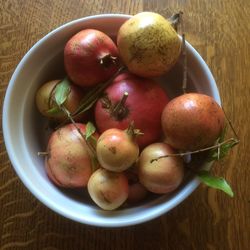 High angle view by natural light of pomegranates filling a white bowl on table