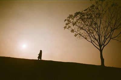 Silhouette person standing on field against sky during sunset