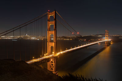 Illuminated golden gate bridge over bay at night