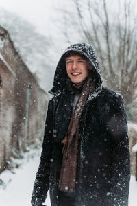 Portrait of smiling young woman standing in snow