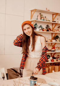 Portrait of a smiling young woman standing against wall