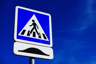 Low angle view of road sign against blue sky