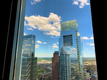 Buildings in city against sky seen through glass window