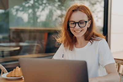 Portrait of young woman using laptop at cafe