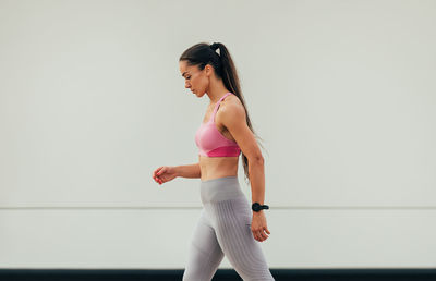 Portrait of young woman exercising against wall