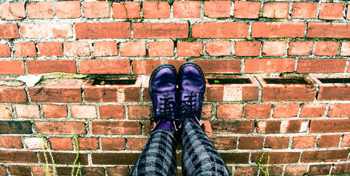 Low section of woman standing on brick wall