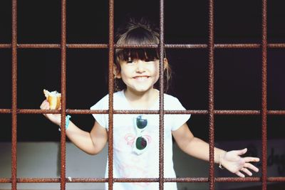 Happy girl holding food seen through metal grate