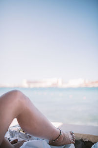 Low section of woman at beach against clear sky