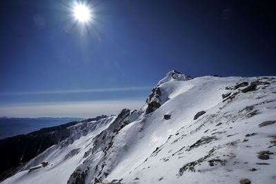 Scenic view of snowcapped mountains against sky on sunny day