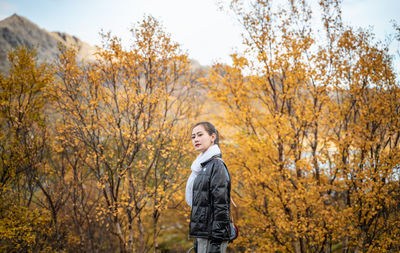 Portrait of teenage girl standing by tree during autumn