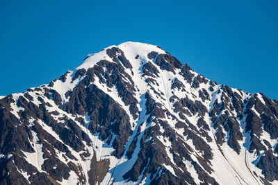 Scenic view of snowcapped mountains against clear blue sky