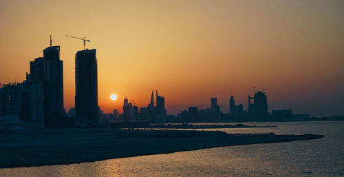 Scenic view of sea and buildings against sky during sunset