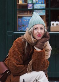 Portrait of young beautiful stylish blonde girl sitting on chair at christmas market