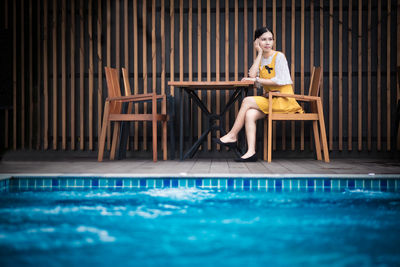 Woman sitting by swimming pool