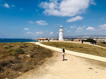 Woman walking on land by sea against sky