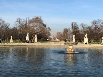 People in park by lake against sky