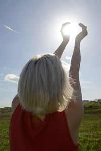 Optical illusion of woman holding sun while standing on grass against sky