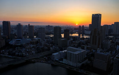 Sunset tokyo cityscape with red sun, skyscrapers and sumida river