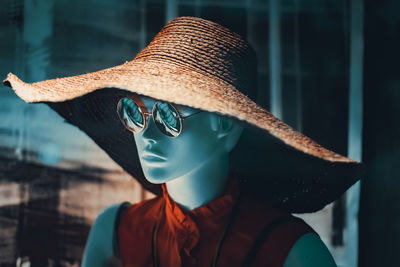 Close-up of mannequin wearing hat against window