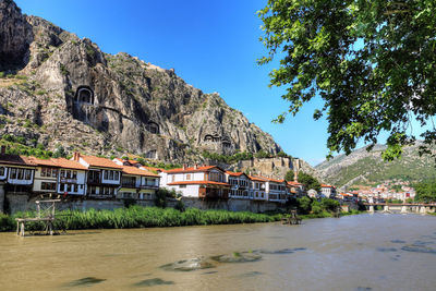 Houses by river and mountains against sky