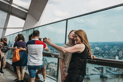 People standing by railing against sky