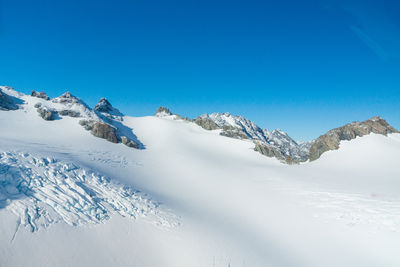 Scenic view of snowcapped mountains against clear blue sky